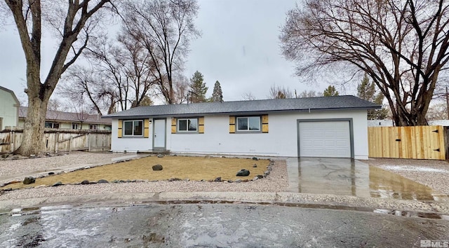 ranch-style house featuring a garage, concrete driveway, fence, and stucco siding