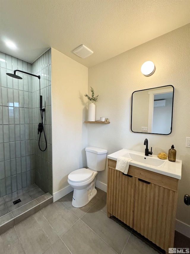 full bathroom featuring toilet, a tile shower, vanity, a textured ceiling, and baseboards