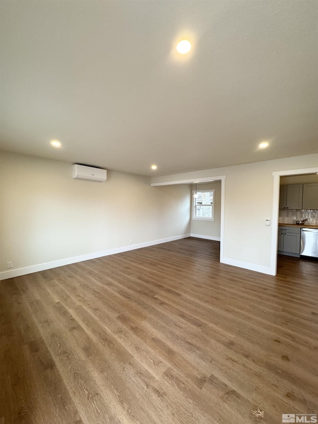 unfurnished living room with recessed lighting, wood finished floors, baseboards, and a wall mounted AC