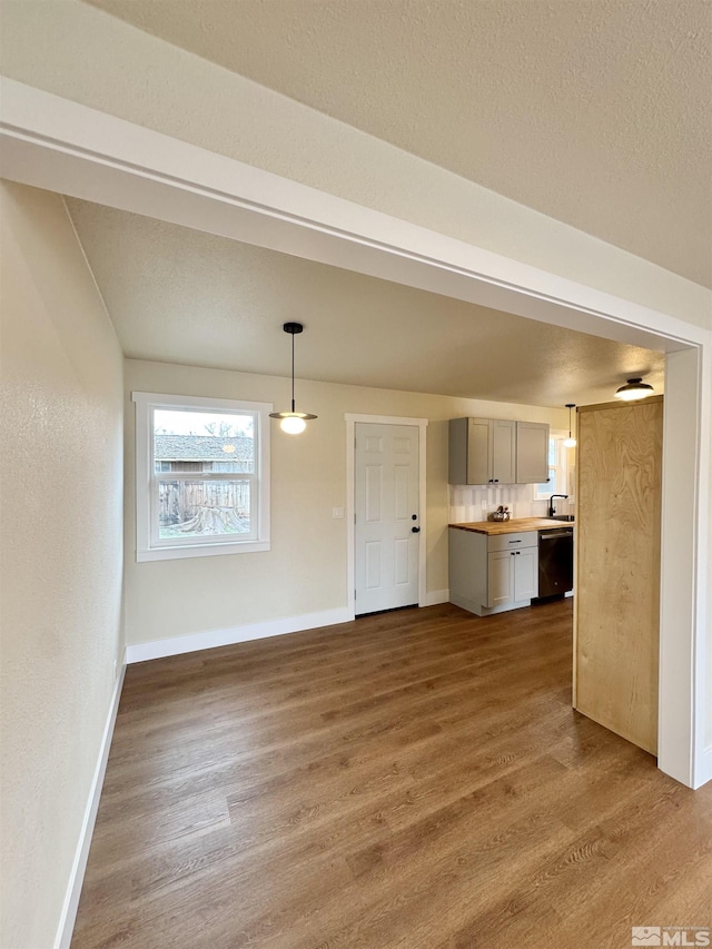 interior space featuring a sink, a textured ceiling, baseboards, and wood finished floors