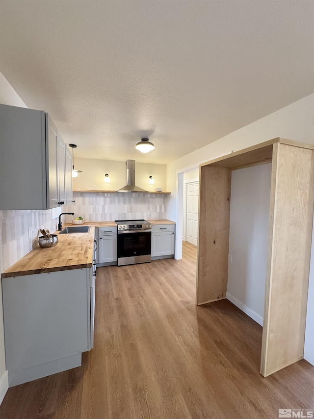 kitchen featuring butcher block counters, a sink, stainless steel electric stove, open shelves, and light wood finished floors