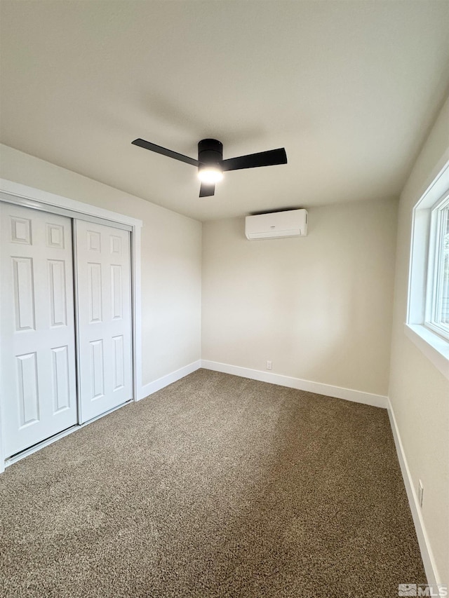 unfurnished bedroom featuring a closet, a wall mounted AC, a ceiling fan, carpet flooring, and baseboards