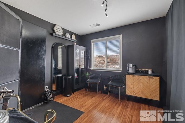 interior space featuring rail lighting, visible vents, and wood finished floors