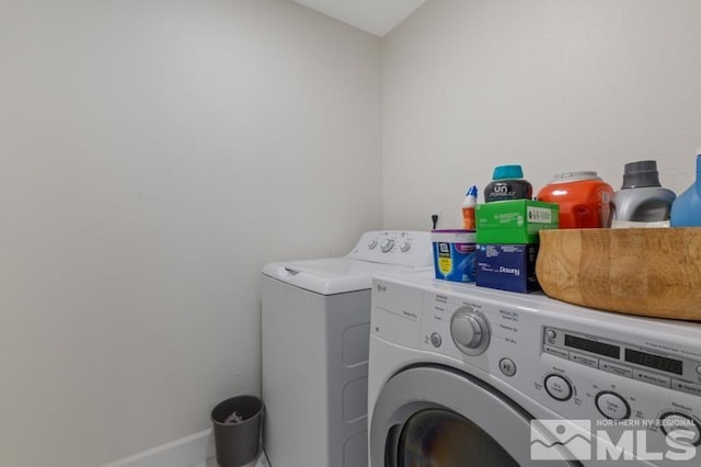 washroom featuring laundry area, baseboards, and separate washer and dryer