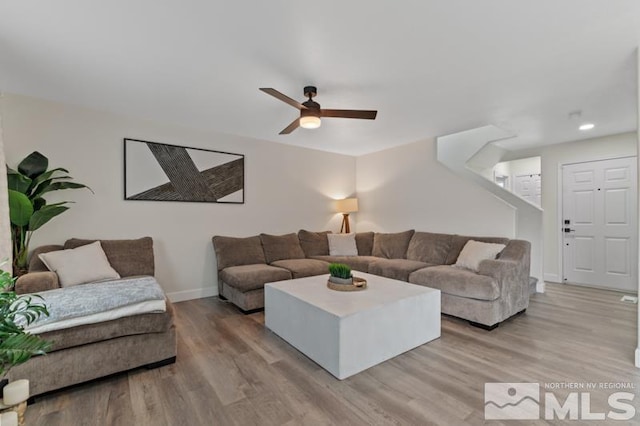 living area featuring light wood-type flooring, baseboards, and a ceiling fan