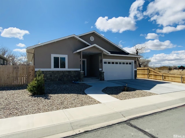 view of front of property featuring stucco siding, concrete driveway, fence, a garage, and stone siding