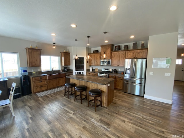 kitchen with appliances with stainless steel finishes, dark countertops, a kitchen island, and a breakfast bar area