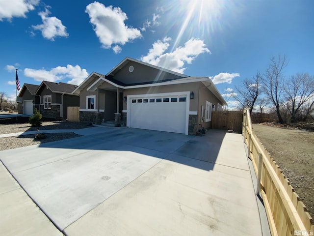 view of front of house with stucco siding, concrete driveway, an attached garage, fence, and stone siding