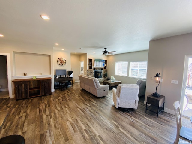 living room featuring baseboards, ceiling fan, wood finished floors, a stone fireplace, and recessed lighting