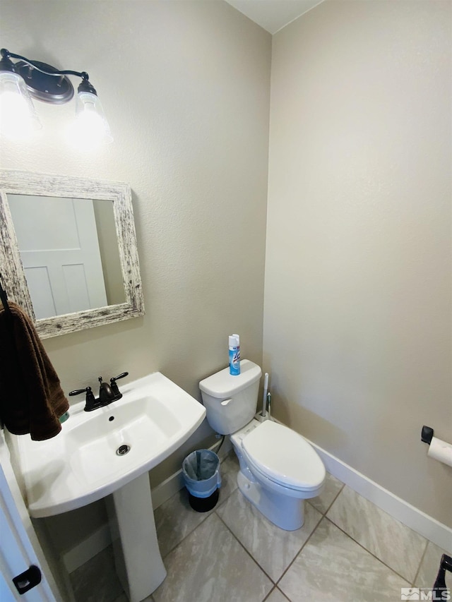 half bathroom featuring toilet, tile patterned flooring, and baseboards