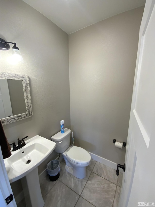 bathroom with a sink, tile patterned flooring, toilet, and baseboards