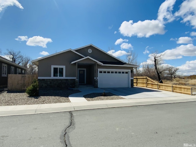 view of front facade with driveway, stone siding, an attached garage, and fence