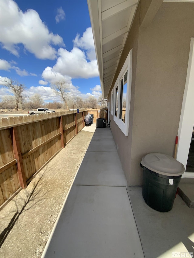 view of side of home featuring a patio, fence, central AC unit, and stucco siding