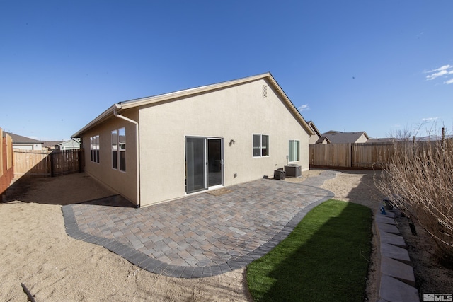 rear view of property featuring a patio, central AC unit, a fenced backyard, and stucco siding