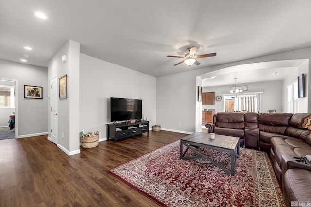 living room featuring dark wood finished floors, recessed lighting, ceiling fan with notable chandelier, and baseboards