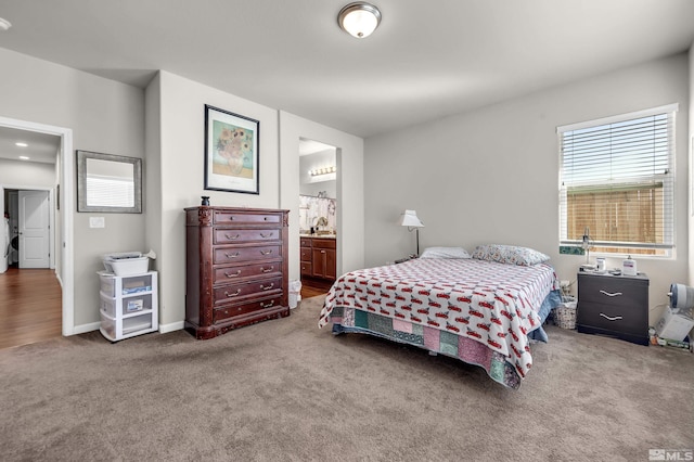 carpeted bedroom featuring ensuite bathroom and baseboards