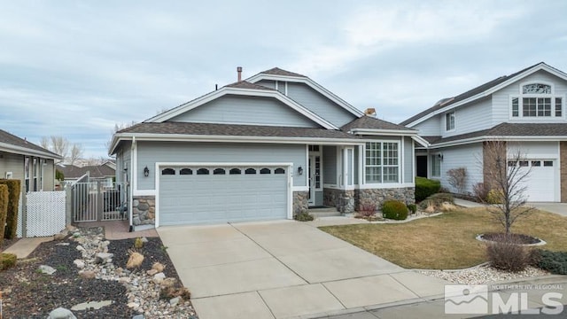 view of front of home featuring a garage, fence, stone siding, driveway, and a gate