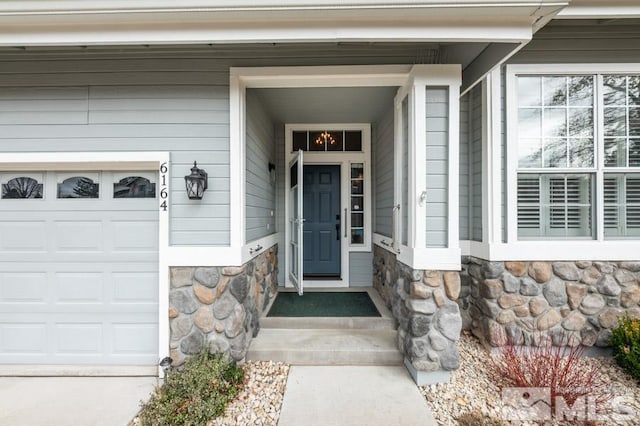 property entrance featuring an attached garage and stone siding