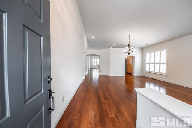 entryway featuring arched walkways, dark wood-style flooring, and baseboards