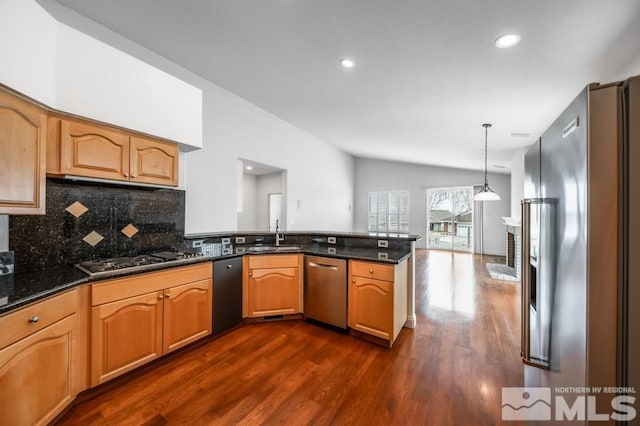 kitchen with a peninsula, dark wood-type flooring, hanging light fixtures, appliances with stainless steel finishes, and backsplash