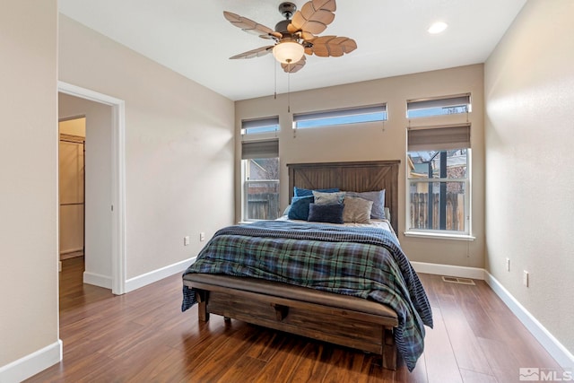 bedroom with ceiling fan, wood finished floors, visible vents, and baseboards