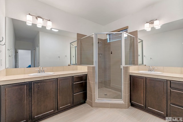 bathroom with a stall shower, two vanities, and a sink