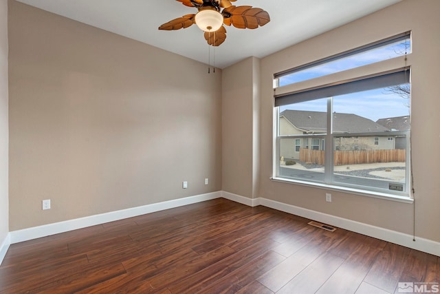 empty room with baseboards, visible vents, ceiling fan, and dark wood-style flooring