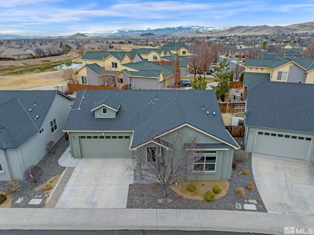 view of front of home with driveway, a shingled roof, a residential view, fence, and a mountain view