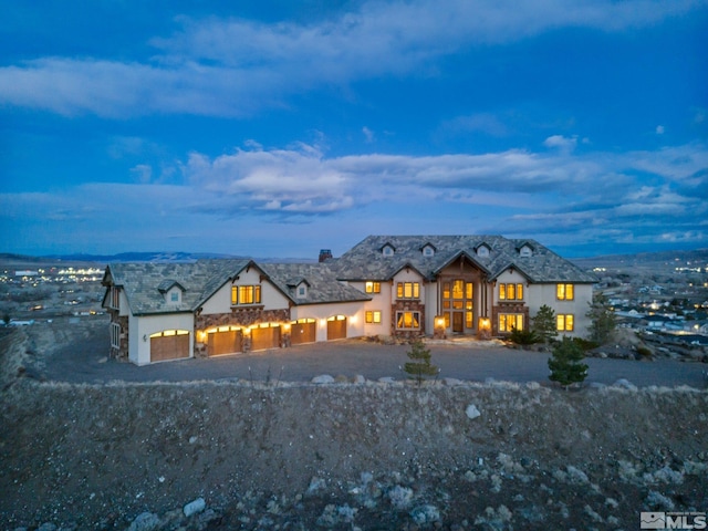 view of front facade with an attached garage, driveway, and stone siding