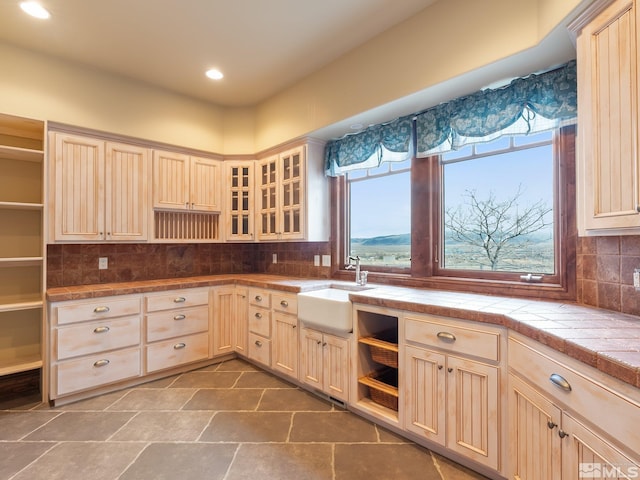 kitchen with glass insert cabinets, a sink, decorative backsplash, and open shelves