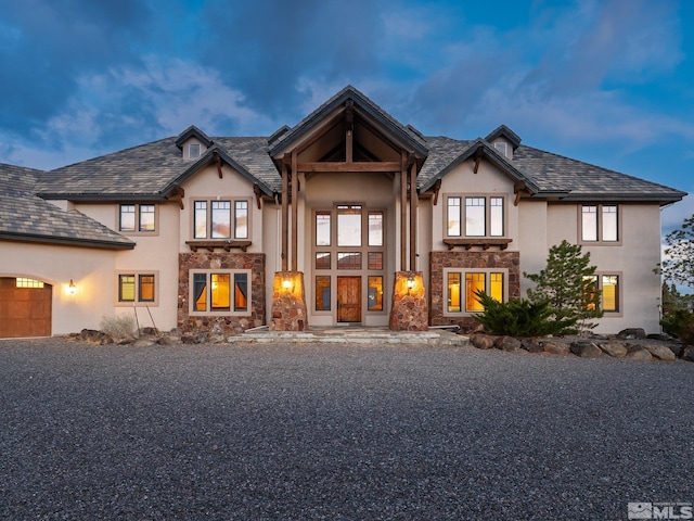 view of front of house with a garage, stone siding, driveway, and stucco siding