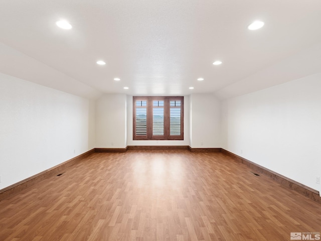 unfurnished room with vaulted ceiling, recessed lighting, light wood-type flooring, and baseboards