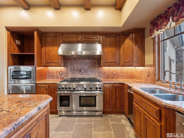 kitchen featuring stone tile floors, range hood, stainless steel appliances, and a sink