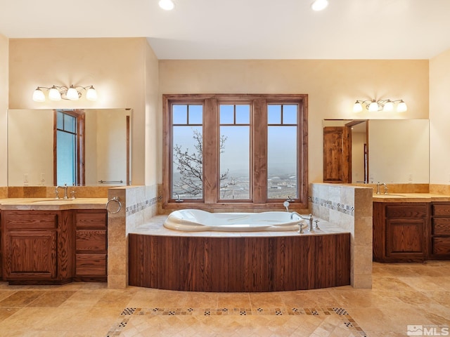 bathroom with a garden tub, two vanities, a sink, and recessed lighting