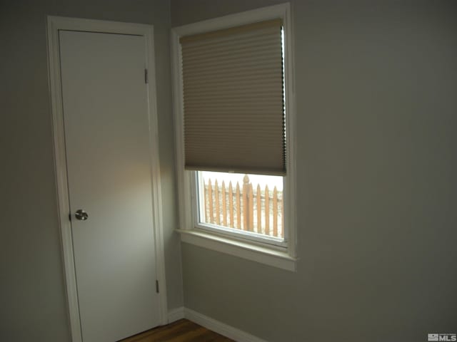 unfurnished bedroom with dark wood-type flooring, a closet, and baseboards