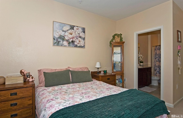 bedroom featuring ensuite bath and baseboards