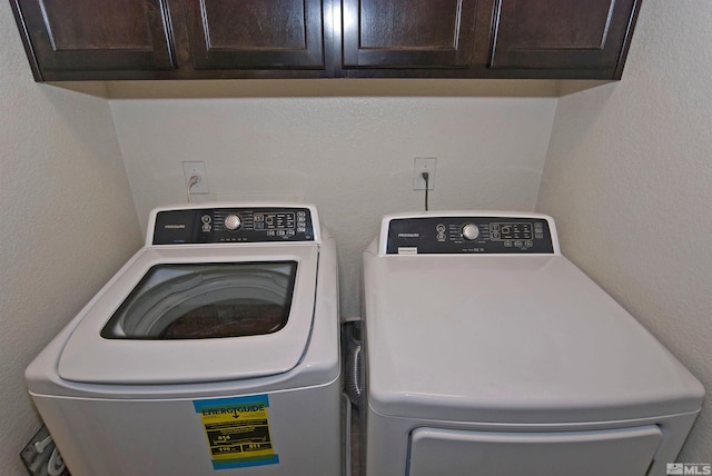 laundry room featuring a textured wall, washing machine and dryer, and cabinet space