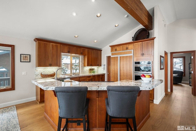 kitchen featuring paneled built in refrigerator, light stone counters, decorative backsplash, and stainless steel double oven