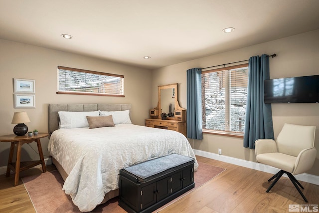 bedroom featuring light wood-style flooring, multiple windows, and baseboards