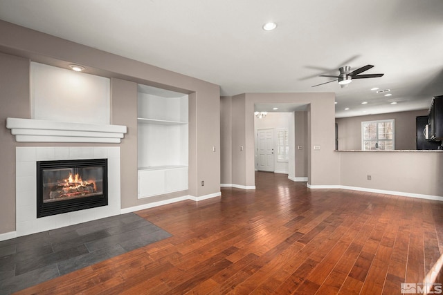 unfurnished living room with hardwood / wood-style floors, recessed lighting, baseboards, and a tile fireplace