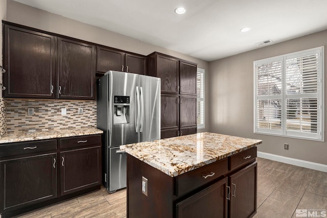 kitchen with visible vents, stainless steel fridge with ice dispenser, dark brown cabinetry, light stone counters, and decorative backsplash