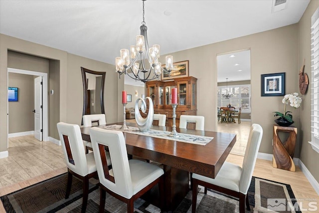 dining area with light wood-style floors, visible vents, baseboards, and an inviting chandelier