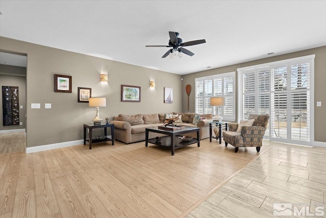 living room featuring light wood-style floors, baseboards, and a ceiling fan