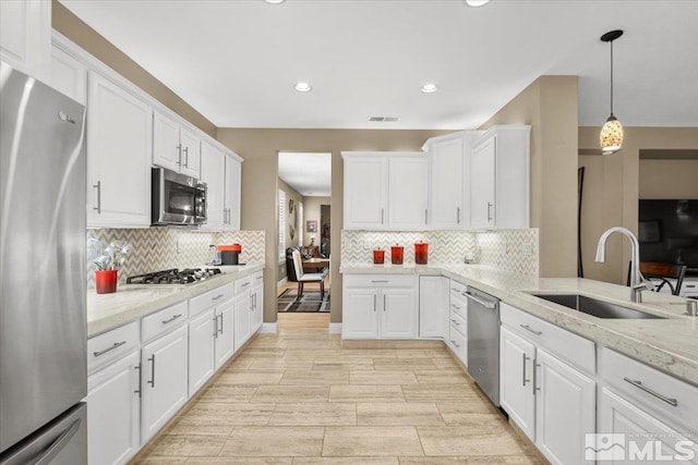 kitchen featuring stainless steel appliances, a sink, visible vents, white cabinetry, and decorative backsplash