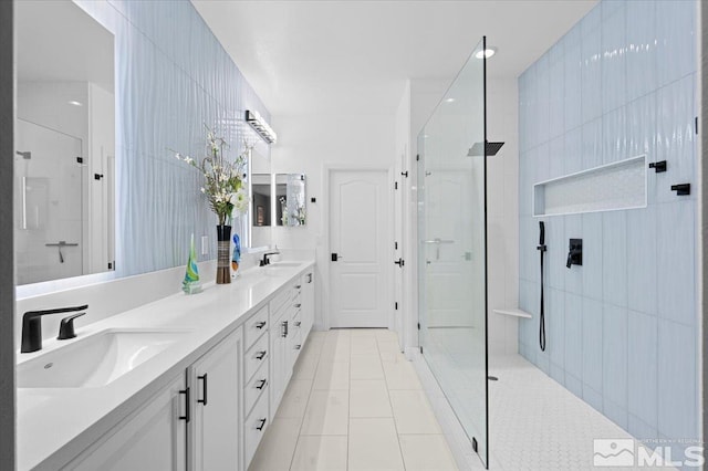 bathroom featuring tile patterned flooring, double vanity, a sink, and walk in shower