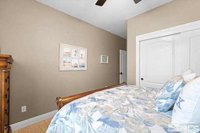 bedroom with a closet, ceiling fan, light wood-style flooring, and baseboards