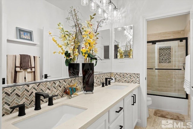 bathroom with a sink, backsplash, toilet, and double vanity