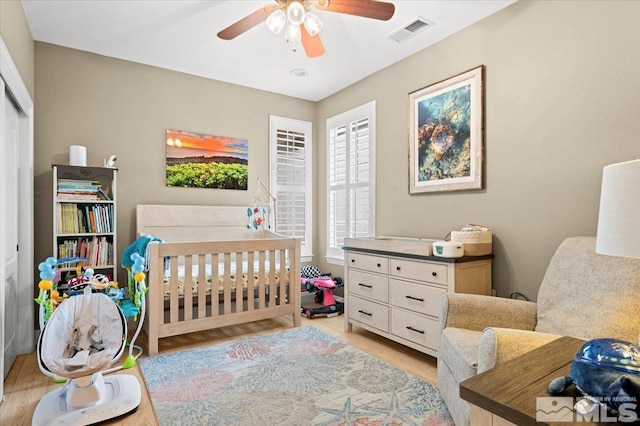 bedroom featuring a ceiling fan, light wood-type flooring, a closet, and visible vents