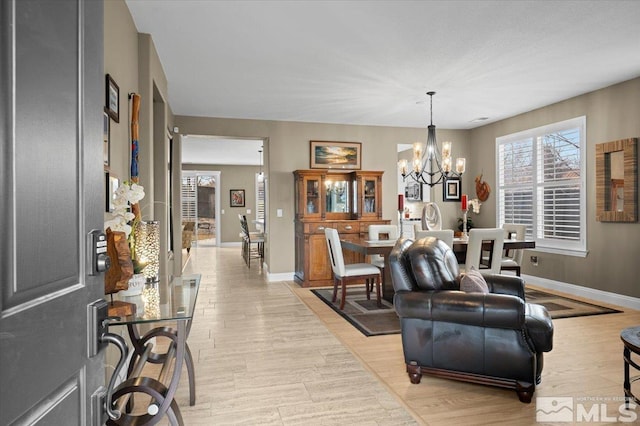 interior space featuring light wood-type flooring, baseboards, and a chandelier