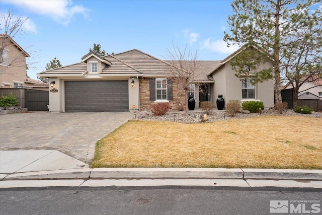 view of front of property with a garage, a tile roof, fence, decorative driveway, and a front lawn